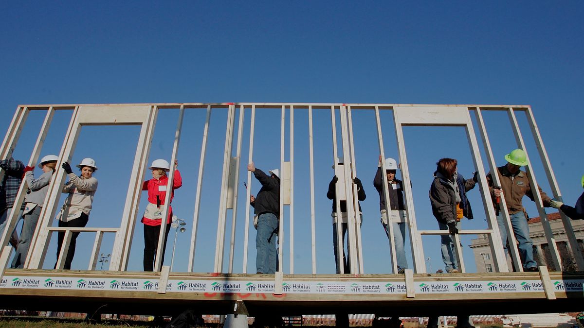 Volunteer workers raise a wooden framing wall on a Habitat for Humanity home under construction in Washington, DC.