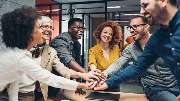 Business team members stack their hands above a table