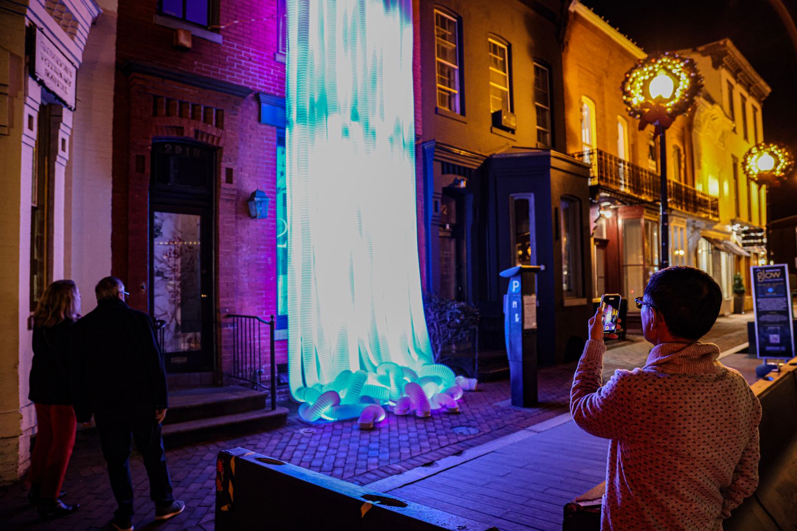 A passerby takes a photo of one of the light displays in 2022's Georgetown GLOW in Washington, D.C.