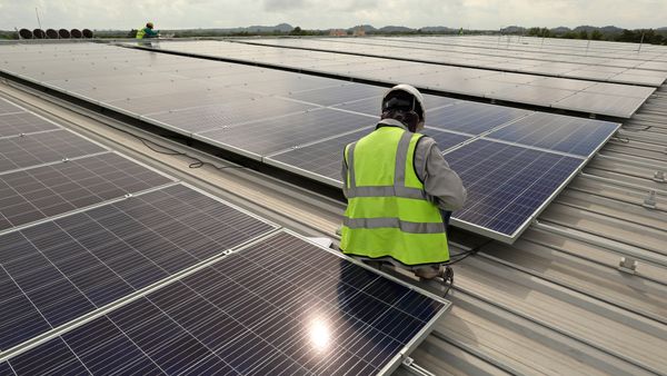 A technician connects cable on a solar rooftop array.